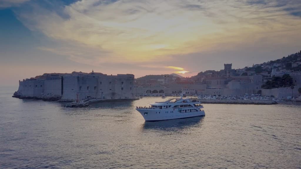 Adriatic cruise ship at sunset near historic coastal walls